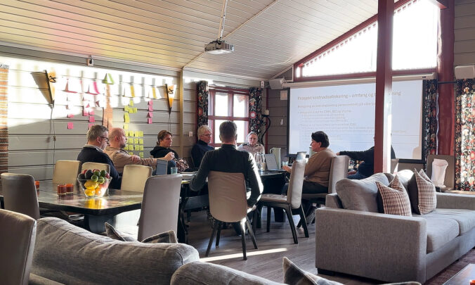 Kursdeltakere sitter rundt møtebordet og følger en presentasjon i Lardalshytta.