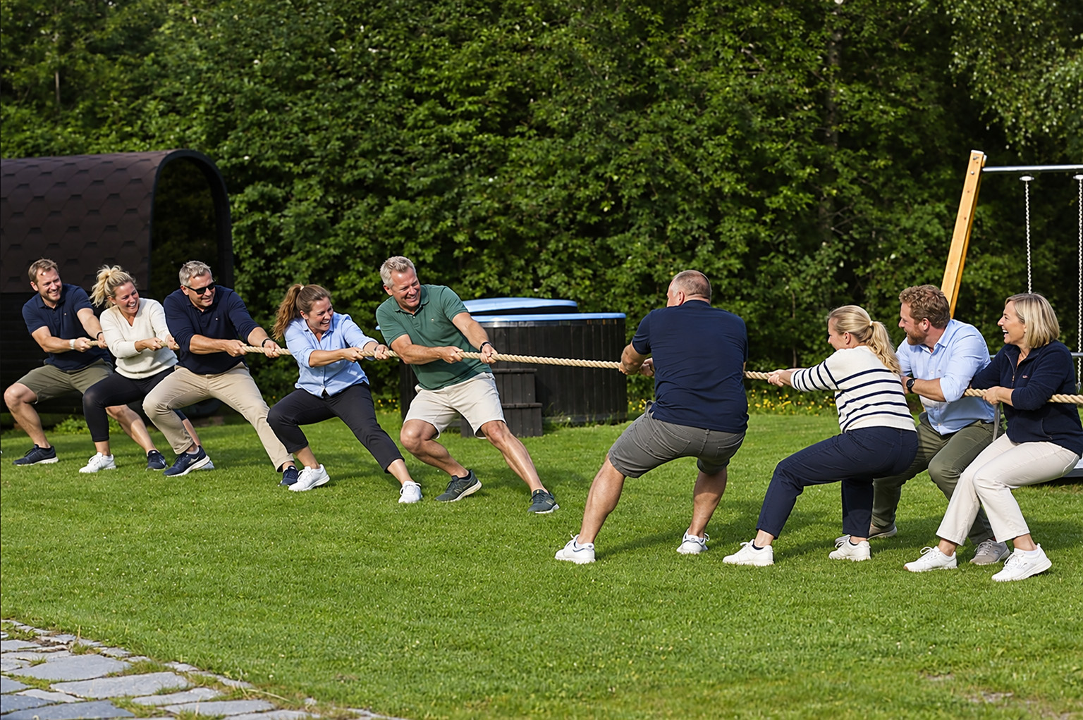 To lag konkurrerer i tautrekking på en grønn gressplen under en teambuildingaktivitet.